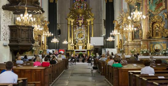 Wnętrze kościoła w perspektywie z jednym punktem zbiegu mającym swój środek na ołtarzu. Na środku przed ołtarzem znadują się cztery kobiety tworzące kwartet smyczkowy. Po bokach siedzą melomani.
