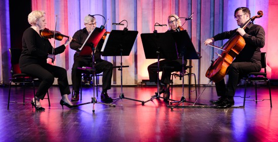 czworo muzyków grających na instrumentach smyczkowych