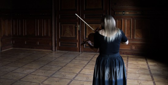 kobieta odwrócona tyłem gra na skrzypcach