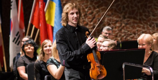 mężczyzna na scenie ze skrzypcami i smyczkiem w ręce