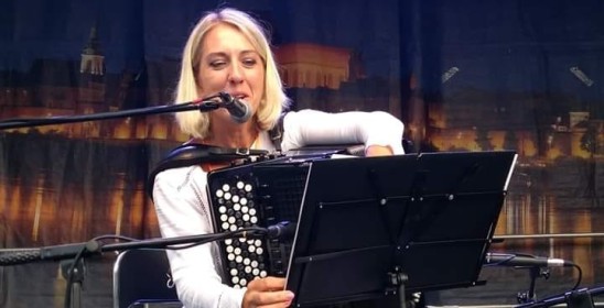 kobieta mówiąca do mikrofonu i trzymająca akordeon