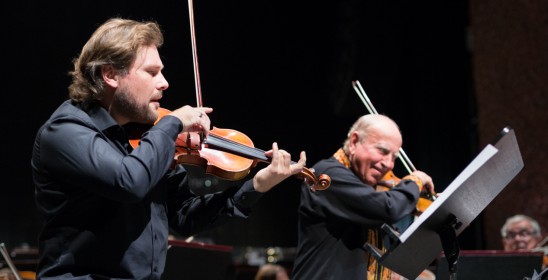 dwóch mężczyzn grających na skrzypcach