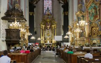 Kościół p.w. Wniebowzięcia Najświętszej Marii Panny w Toruniu, po obu stronach ławki z siedzącą publicznością w dali przed płtarzem siedzą cztery kobiety