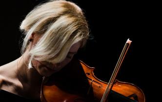 kobieta z opadającymi blond włosami na twarz gra na skrzypcach