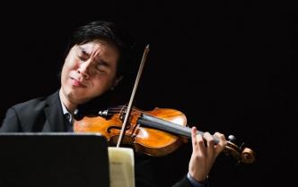 mężczyzna w ciemnych włosach z przymkniętymi oczami gra na skrzypcach