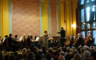 muzycy na scenie z przodu dyrygent obok solistka skrzypaczka