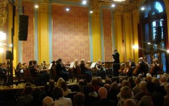 orkiestra na scenie, z przodu głowy siedzącej publiczności