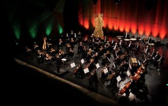 zdjęcie zrobione z góry widać na scenie orkiestrę - kobiety i mężczyźni grają na instrumentach przed nimi dyrygent - Dainius Pavilionis