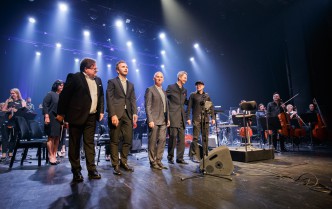 pięcioro mężczyzn stojących w rzędzie na scenie