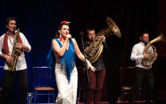 kobieta w niebiesko białej sukni i trzech mężczyzn grających na instrumentach dętych