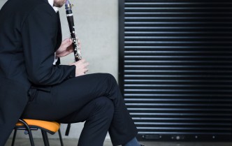 siedzący mężczyzna i grający na klarnecie
