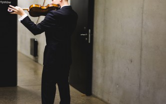 mężczyzna stojący tyłem i grający na skrzypcach