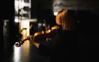 kobieta stojąca tyłem i grająca na skrzypcach