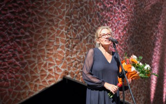kobieta trzymająca kwiaty i mówiąca do mikrofonu