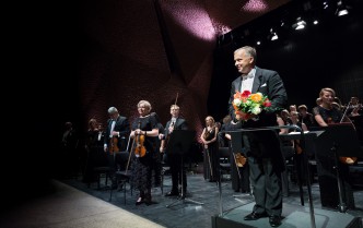 orkiestra na scenie i dyrygent trzymający bukiet kwiatów