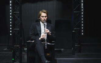 siedzący mężczyzna gra na klarnecie