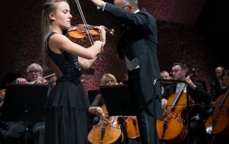 kobieta grająca na skrzypcach i dyrygent z uniesionymi rękoma