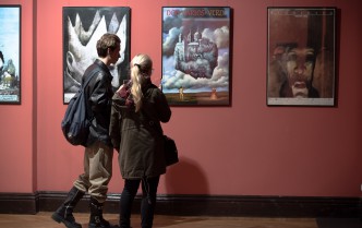 kobieta i mężczyzna oglądający plakaty wiszące na ścianie