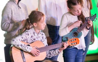 piątka dzieci śpiewa oraz gra na gitarze akustycznej i ukulele 
