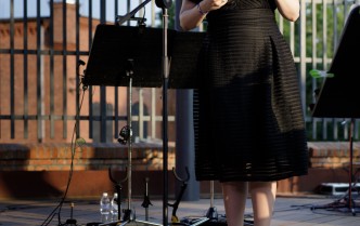 kobieta w czarnej sukni trzymająca teczkę przemawia do mikrofonu