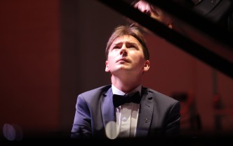 zbliżenie na twarz mężczyzny patrzącego w górę i grającego na fortepianie