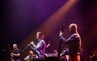 grupa mężczyzn zespołu ukazana na scenie w trakcie koncertu