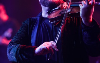 mężczyzna w czerwonym świetle grający na skrzypcach
