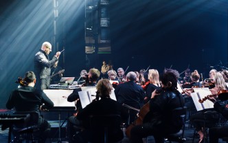 muzycy orkiestry i stojący nad nimi dyrygent