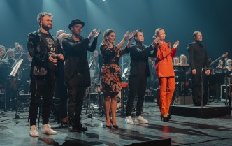 grupa wokalistów stojąca wspólnie na scenie