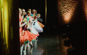 grupa baletnic w różnych, kolorowych sukniach ukazana w rzędzie