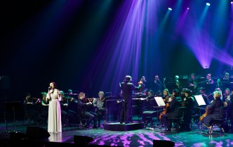 wokalistka ukazana na scenie z dalekiej perspektywy w fioletowo-różowym świetle