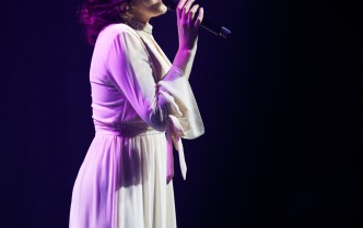 wokalistka w białej sukni śpiewająca na scenie