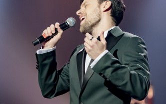 mężczyzna w garniturze śpiewający do mikrofonu