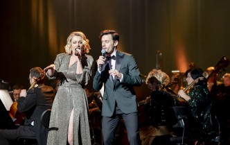 mężczyzna w garniturze i kobieta w cekinowej sukni wspólnie śpiewają na scenie