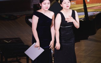dwie kobiety stojące przed fortepianem