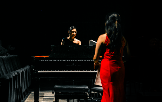 dwie kobiety stojące przy fortepianach