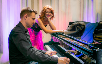 mężczyzna grający na fortepianie i kobieta opierająca się o fortepian