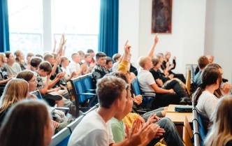 widownia młodzieży, niektóre z osób mają podniesione ręce zgłaszając się do odpowiedzi