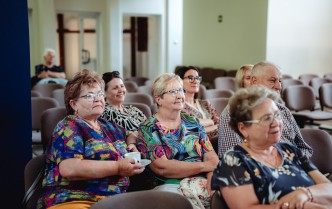 grupa starszych osób, w większości kobiet słuchających koncertu