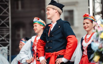 na pierwszym planie mężczyzna stroju kujawskim, za nim w tle dwie kobiety w stroju