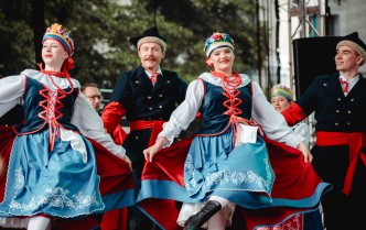 dwie kobiety w stroju kujawskim, przy każdej z nich mężczyźni w strojach, wszyscy tańczą