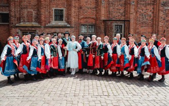 zespół tancerzy w strojach kujawskich, pozujący w rzędzie do zdjęcia