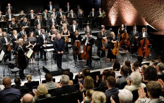 orkiestra stojąca na scenie w górnej części fotografii, w dolnej widać publiczność