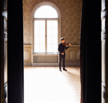 mężczyzna gra na skrzypcach w oświetlonym pokoju