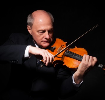 mężczyzna gra na skrzypcach na ciemnym tle