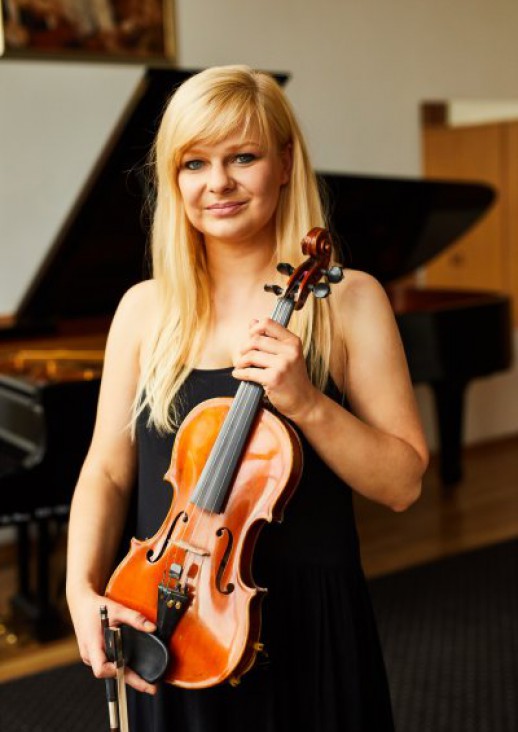 young blonde woman in a black dress with bare shoulders holding a violin in her hands