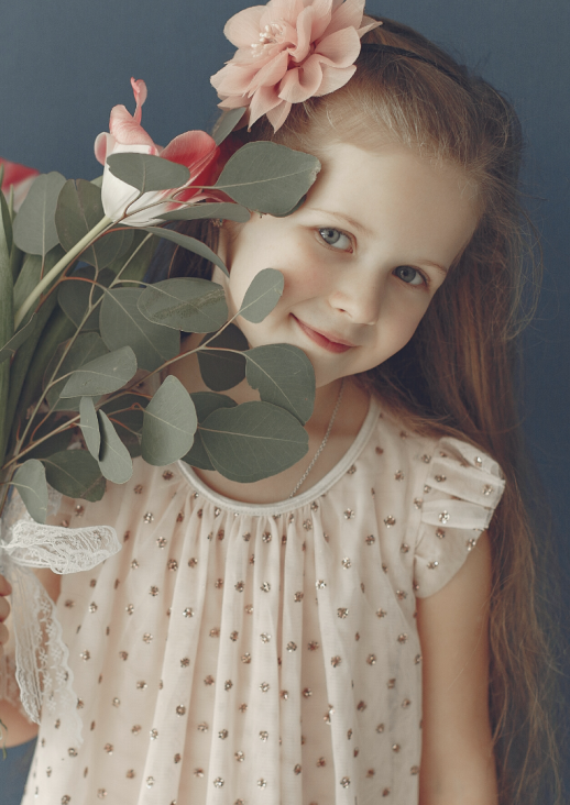 grafika prezentująca uśmiechniętą dziewczynkę trzymającą kwiatek i tytuł koncertu
