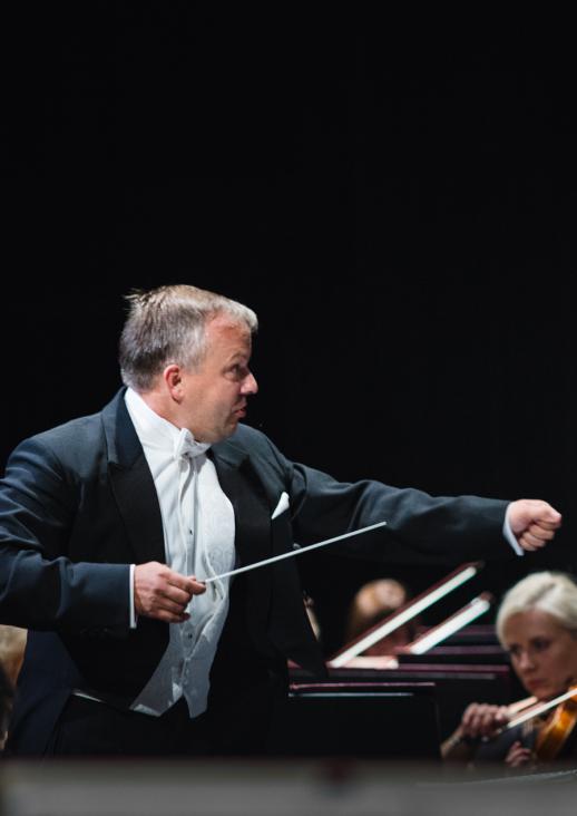 conductor holding the baton in one hand with the other hand extended