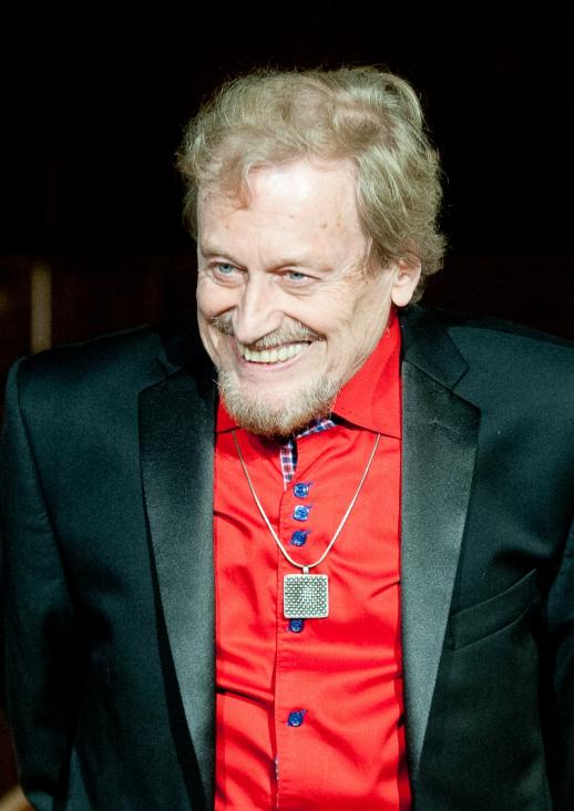 An older man in a red shirt and tuxedo