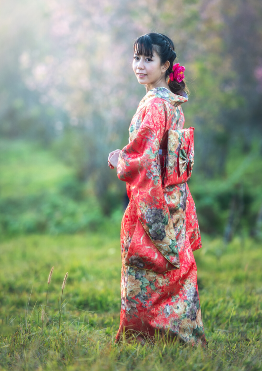A young Asian woman in a kimono on a meadow and information about the concert